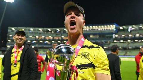 Ben Charlesworth roars in celebration as he holds the T20 Blast trophy.