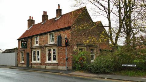 A red brick building with a sign reading "The Royal Oak" on the corner of a street.