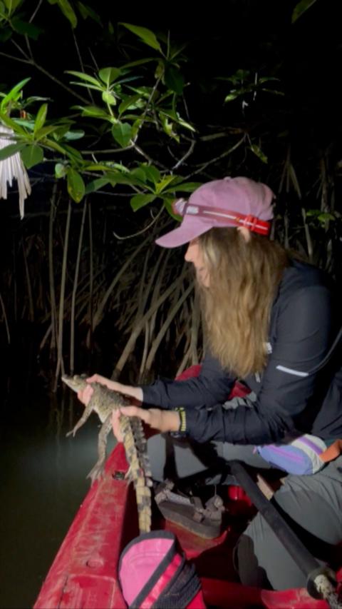 Crocodile attack survivor Georgia Laurie on a boat in Central America. She is holding a small crocodile.