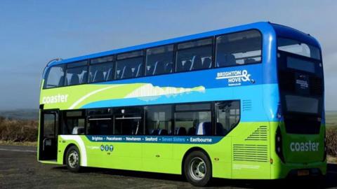 A blue and green double-decker bus parked on a roadside