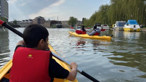 Boy in a boat and other boats moored on river in Peterborough