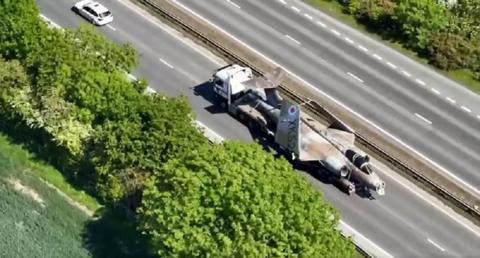 A Buccaneer fighter jet on the back of a lorry makes its way along a dual carriageway