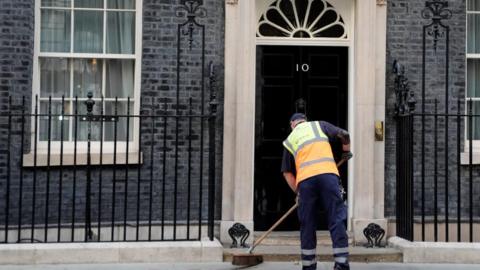 A man sweeping the road outside 10 Downing Street.