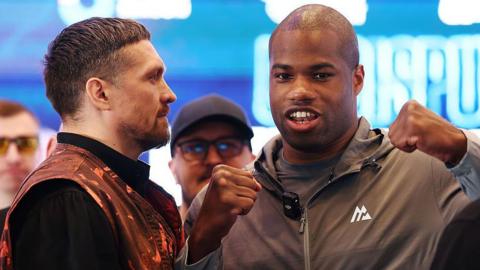 Oleksandr Usyk stares at Daniel Dubois, who breaks the face-off and flexes 