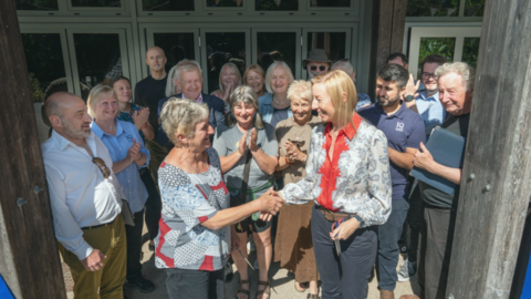 A celebratory hand-shake in front of a crowd at the centre's front door