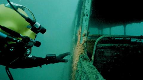 Diver exploring a double decker bus underwater