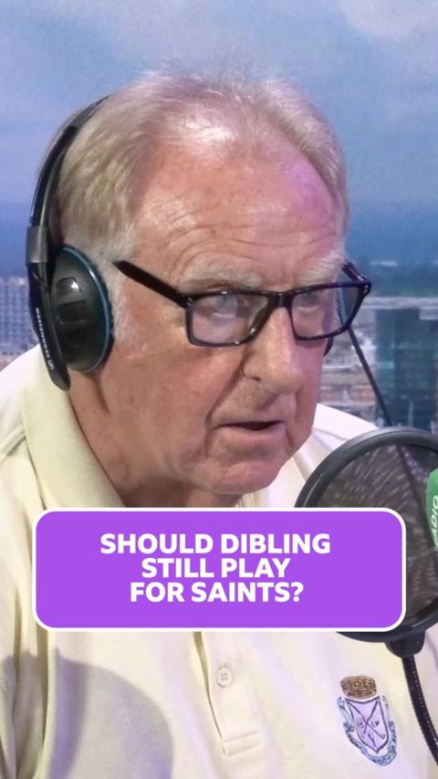 Older man in a yellow polo top sits in a radio studio with headphones on.