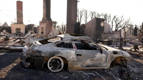 A burned car and building in Los Angeles