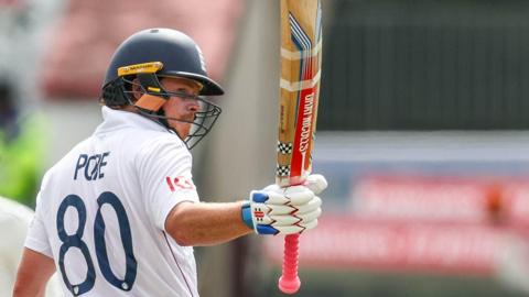 Ollie Pope raises his bat after reaching a milestone