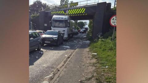 A lorry under a bridge with debris on the floor