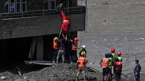 Police personnel rescue stranded residents from houses lying deluged in sludge after flash floods at Trishuli in Nepal's Nuwakot district on August 27, 2026.
