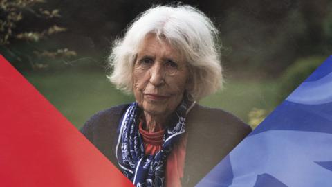 Heather looks at the camera. The two corners of the image show a red triangle and a blue triangle
