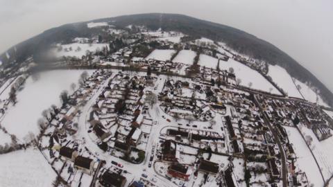 An aerial photo looking down at a snow-covered rural village and surrounding landscape in the West country. Similar scenes are possible by late Saturday, especially across Gloucestershire.