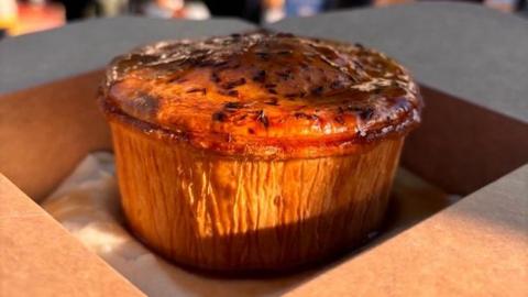 Pie and mash, covered with gravy, in a cardboard takeaway box