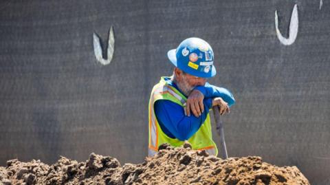 A construction worker takes a quick break while digging a trench with a shovel amidst a heat wave in Irvine Thursday, Sept. 5, 2024