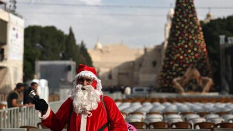A man dressed as Santa Claus stands in Manger Square ahead of the lighting of the Christmas tree in the West Bank city of Bethlehem