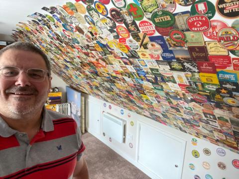 Rob in front of a wall covered in various beermats