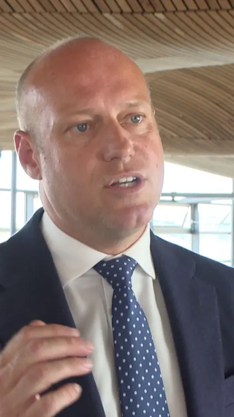 Dan Thomas, the leader of Reform UK Wales, who has a bald head and blue eyes