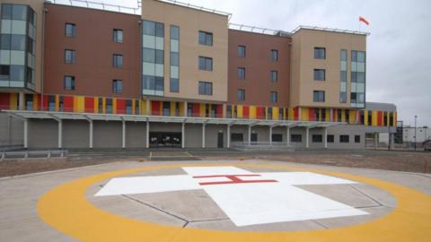 A multi-storey building with a large helicopter landing pad in the foreground