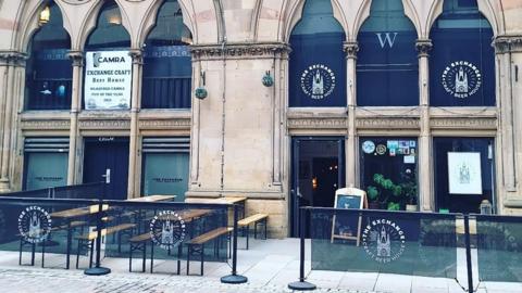 General view of the Exchange Craft Beer House, a city pub building with seating outside.