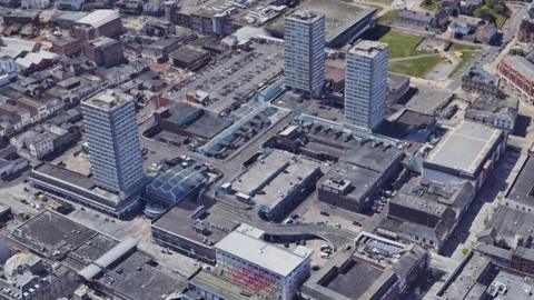 Aerial view of Sunderland City Centre. There are three tall tower blocks surrounding a shopping centre and various other buildings and plazas around.