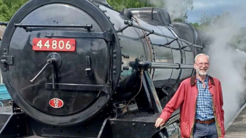 Peter Best standing with a train to his right