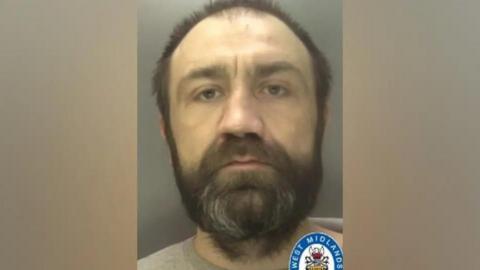 Custody photo of middle-aged prisoner with dark beard