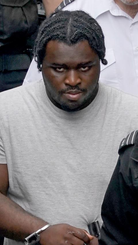 A man wearing handcuffs staring towards the camera