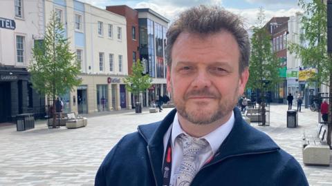 A head and shoulders picture of Sergeant Christian Denning from Essex Police in a pedestrianised area of Chelmsford city centre