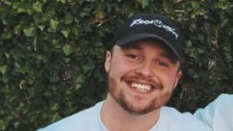 Kai Roberts wearing a black hat and smiling at the camera. 