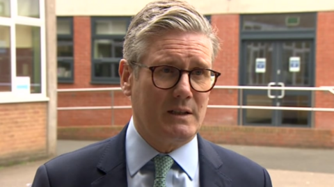 Sir Keir Starmer in a dark blue suit and green patterned tie