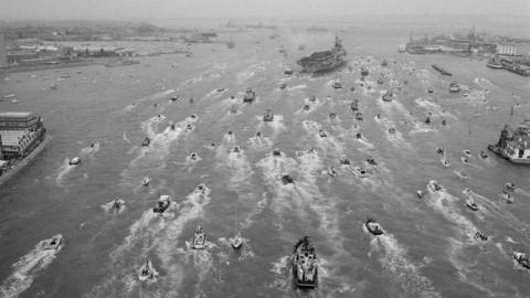 A Royal Navy aircraft carrier, possibly HMS Hermes, is met by a flotilla of small vessels on its return to Portsmouth from the south Atlantic after the Falklands War, 30th July 1982.