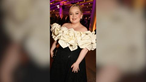 Actor Nicola Coughlan wears a dress with a black skirt and a puffy wide bodice