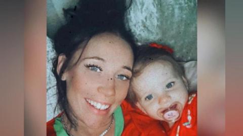 Kerry Blackaller, a woman with black hair, lies down with her daughter. They have matching red tops on.