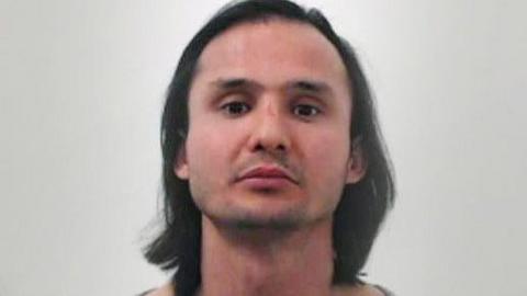 A mugshot of Sadeq Nikzad who had long shoulder length black hair and a moustache