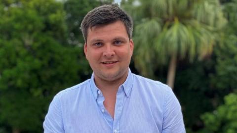 A man with short dark hair wearing a blue shirt