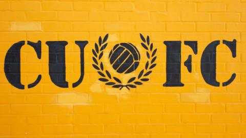 Yellow wall decorated with Cambridge United FC initials