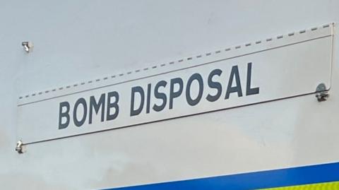 The words "BOMB DISPOSAL" on the side of a police vehicle.