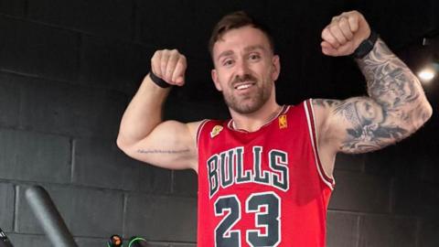 Luke flexes his muscles on the stairclimbing machine and smiles ahead of his challenge.