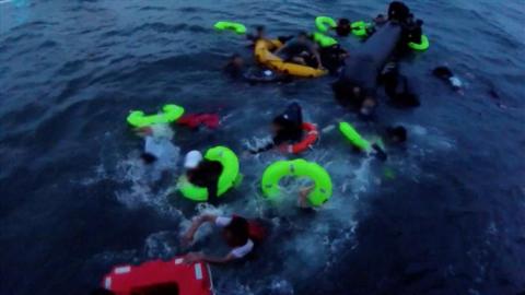 A number of people in the sea. Some have inflatables. 