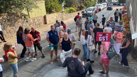 A number of people with Say no to GST placards standing outside Guernsey's Royal Court.