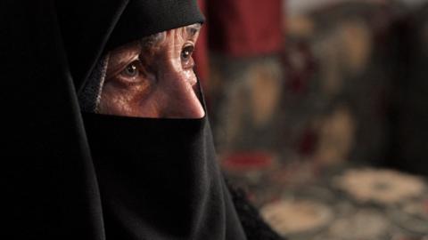 Close up side view of the face of Samira, a Syrian mother. She is wearing a black veil and only her eyes are visiblees are