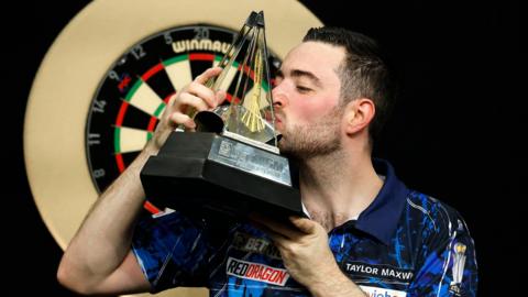 Luke Humphries celebrates with the Premier League Darts trophy