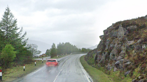 A single carriageway road snakes round a low cliff. The words "slow" are written on either side of the road.