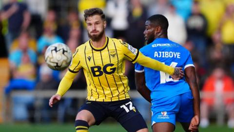 Joe Bennett holds off a player as he goes for the ball during a match