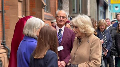 Queen Camilla speaks to a group of women up close. 