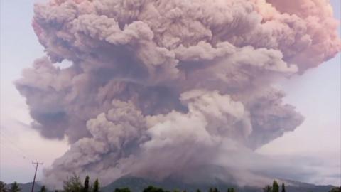 Huge plumes of purple and pink-hued smoke are seen from above Mount Lewotobi