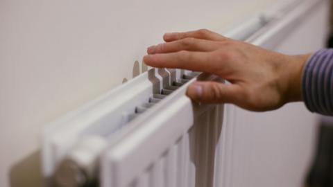 A person checks the heat coming out of a radiator