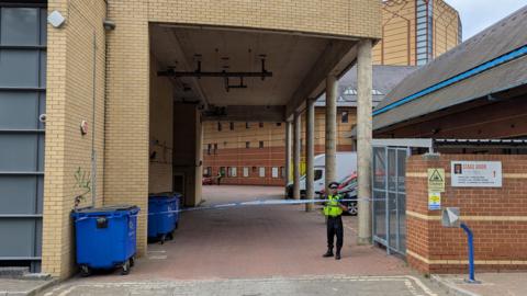 A police officer stands guard next to some police tape.
