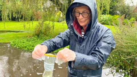 Kate Riley collects a water sample from the River Tillingbourne